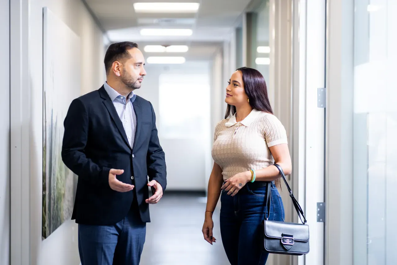 Two professionals engaged in conversation indoors.